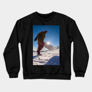 Snowboarder walking against blue sky Crewneck Sweatshirt